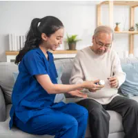 A female caregiver giving medication to an elderly man