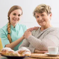 A female caregiver and an elderly woman smiling