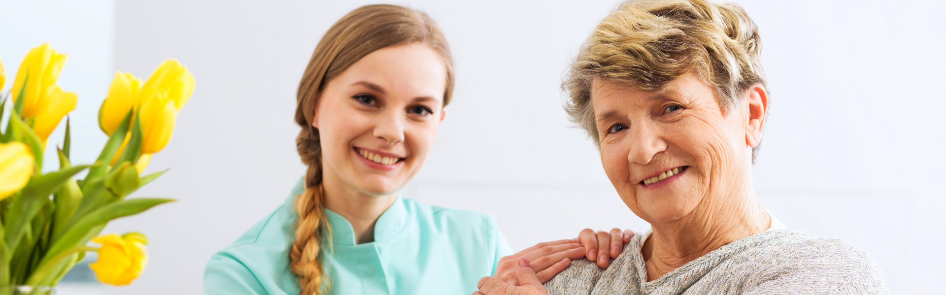 A female caregiver and an elderly woman smiling