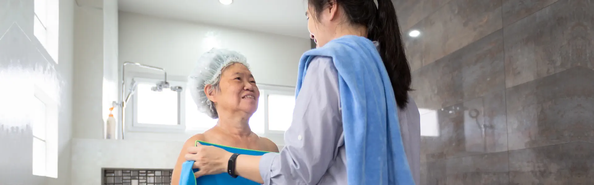 An elderly woman taking a bath and being assisted by a female