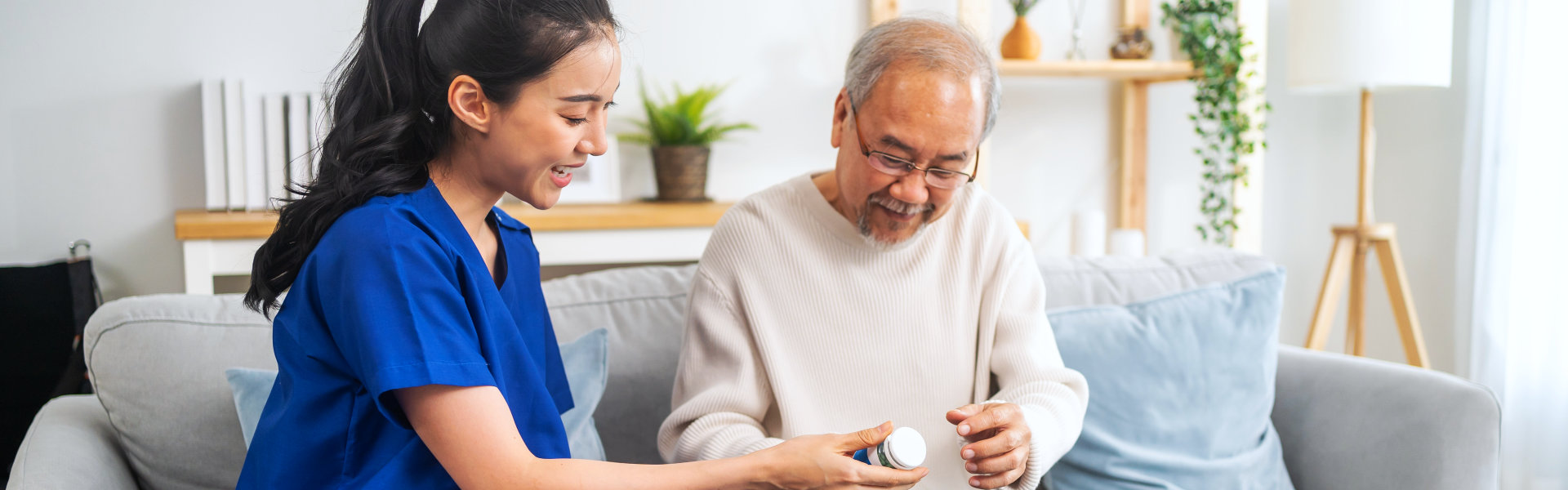 A female caregiver giving medication to an elderly man